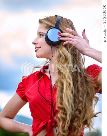 Student girl with backpack headphone listen music on green grass 53563650