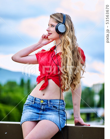 Student girl with backpack headphone listen music on green grass 53563670