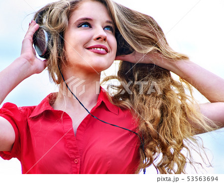 Student girl with backpack headphone listen music on green grass 53563694