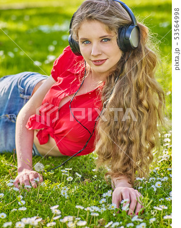 Girl in headphones catch rhythm music on green grass Girl in headphones catch rhythm music on green grass 53564998