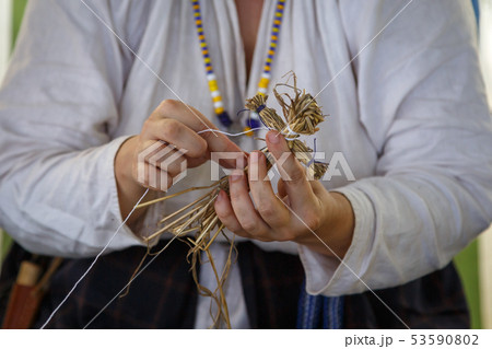 Woman in a white shirt makes a straw toy 53590802