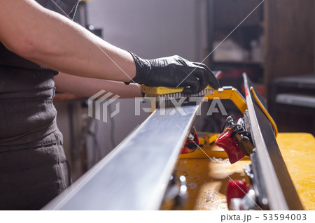 Work and repair concept - a man's hands repairing the ski by rubbing a paraffin Work and repair concept - a man's hands repairing the ski by rubbing a paraffin 53594003