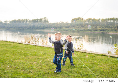 Children and childhood concept - Two brothers boys playing with colorful soap bubbles 53594803