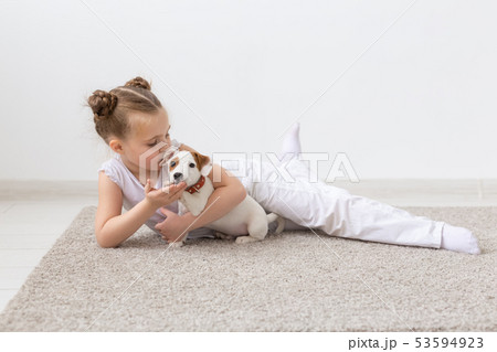 Childhood, pets and dogs concept - Little child girl posing on the floor with puppy 53594923