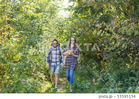 Travel, adventures, hike, tourism and nature concept - Tourist couple with cat walking in the woods Travel, adventures, hike, tourism and nature concept - Tourist couple with cat walking in the woods 53595154