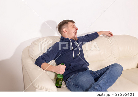 Depression and alcoholism concept - Aggressive male alcoholic sitting on the sofa Depression and alcoholism concept - Aggressive male alcoholic sitting on the sofa 53595401