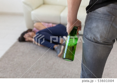 Victim, domestic violence, abuse and alcoholic concept - drunk man with bottle near his wife lying 53601084