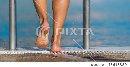 Female feet on the steps of the pool 53613380