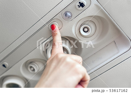 Woman hand up to adjust console panel at the air conditioner above the seat in cabin of low cost 53617162