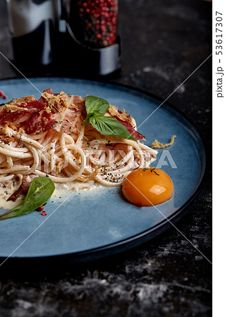 Classic pasta carbonara with yolk on a plate. Pasta laid out on a blue plate on a dark background 53617307