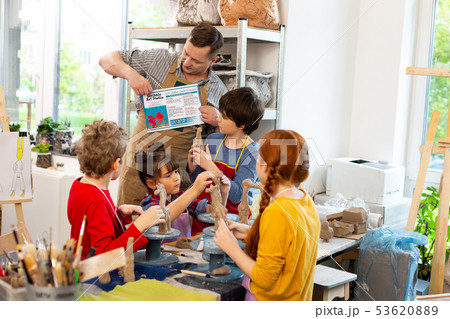 Teacher telling his pupils about sculpting clay figures 53620889