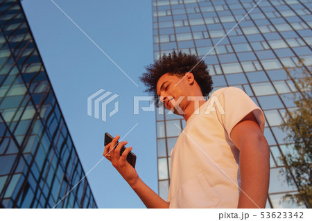 happy smiling urban hipster young man using smart phone. African american teenager holding mobile happy smiling urban hipster young man using smart phone. African american teenager holding mobile 53623342