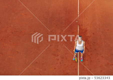 Aerial shot of a female tennis player on a court during match. Young woman playing tennis.High angle Aerial shot of a female tennis player on a court during match. Young woman playing tennis.High angle 53623343