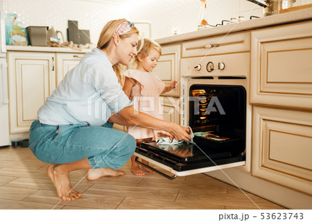 Mother and kid remove from the oven baking sheet Mother and kid remove from the oven baking sheet 53623743