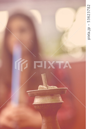 Young woman smoking a hookah outdoors. The pleasure of smoking. City in background 53623782