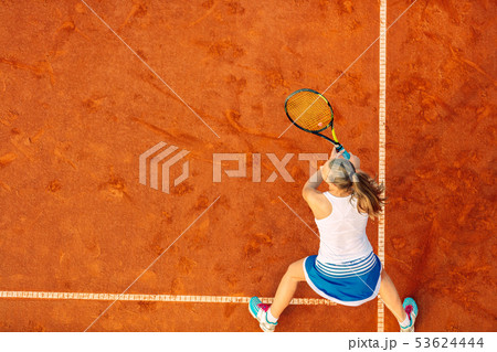 Aerial shot of a female tennis player on a court during match. Young woman playing tennis.High angle Aerial shot of a female tennis player on a court during match. Young woman playing tennis.High angle 53624444
