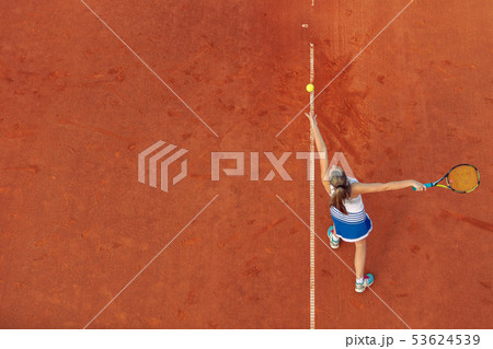 Aerial shot of a female tennis player on a court during match. Young woman playing tennis.High angle Aerial shot of a female tennis player on a court during match. Young woman playing tennis.High angle 53624539