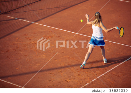 Young woman playing tennis on clay. Forehand. Young woman playing tennis on clay. Forehand. 53625059