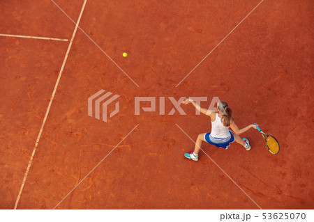 Aerial shot of a female tennis player on a court during match. Young woman playing tennis.High angle Aerial shot of a female tennis player on a court during match. Young woman playing tennis.High angle 53625070