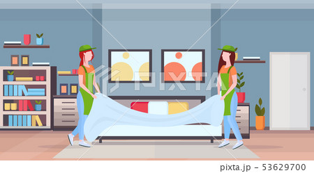 couple chambermaids changing the bedding or bedclothes girls in uniform working together cleaning couple chambermaids changing the bedding or bedclothes girls in uniform working together cleaning 53629700