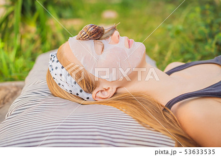 Young woman makes a face mask with snail mucus. Snail crawling on a face mask 53633535