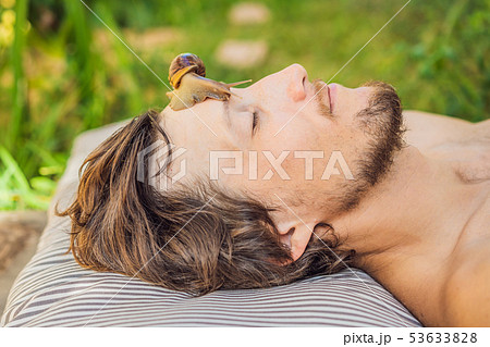 Young man makes a face mask with snail mucus. Snail crawling on a face mask. SPA for man, SPA for Young man makes a face mask with snail mucus. Snail crawling on a face mask. SPA for man, SPA for 53633828