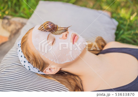 Young woman makes a face mask with snail mucus. Snail crawling on a face mask 53633870
