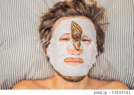 Young man makes a face mask with snail mucus. Snail crawling on a face mask. SPA for man, SPA for Young man makes a face mask with snail mucus. Snail crawling on a face mask. SPA for man, SPA for 53634581