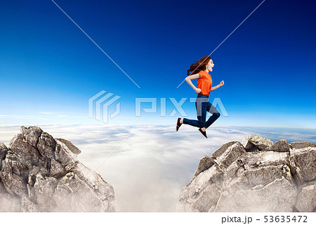 Redhead woman jumps through the gap between hills. 53635472