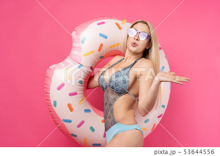 Image of girl in swimsuit sunglasses with inflatable donut for swimming on empty pink background 53644556