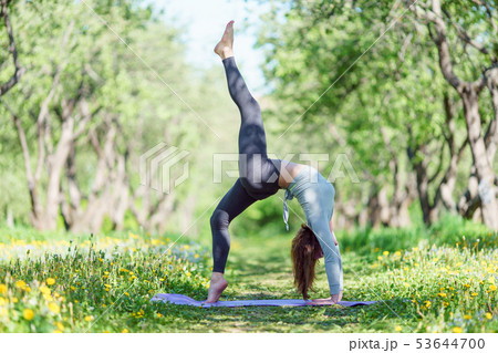 Photo of woman doing yoga on blue rug in woods 53644700