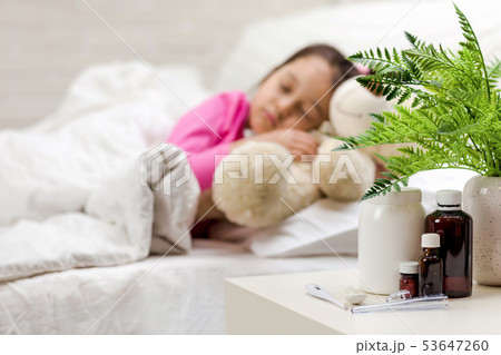 Sick little girl lying in bed with thermometer 53647260