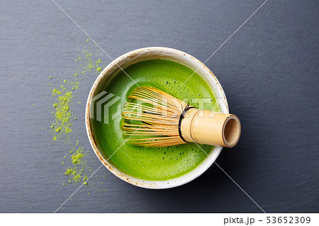 Matcha green tea cooking process in a bowl with bamboo whisk. Black slate background. Top view. 53652309