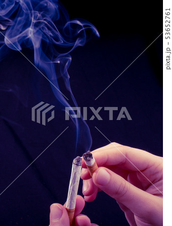 Hand is holding smoking cigarette on black Hand is holding smoking cigarette on black 53652761