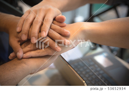 Business people join hands over laptop in office. 53652934