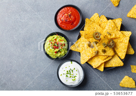 Nachos chips on a plate with sauces, dip variety. Grey stone background. Top view. Copy space. 53653677