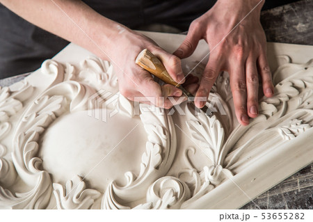 Hands of the sculptor with the tool. The sculptor works in the Studio. Creation of a decorative 53655282