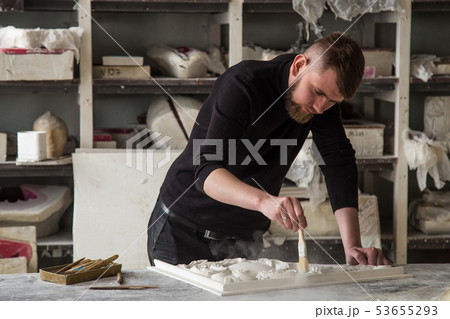The sculptor works in the Studio. Creation of a decorative element from plaster. Luxurious stucco in 53655293