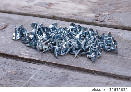 Heap of metal screws on wooden background close up. 53655833