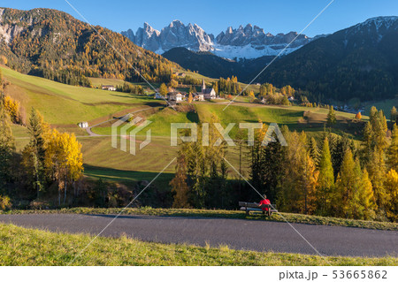 Tourist on bench looks at beautiful Dolomites 53665862