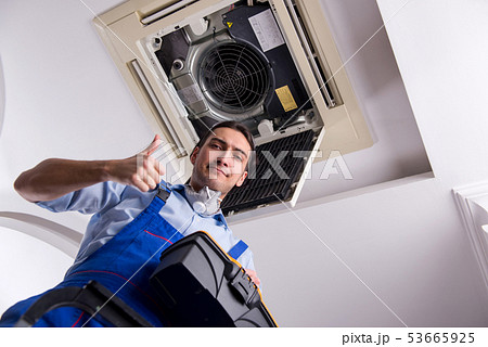 Young repairman repairing ceiling air conditioning unit Young repairman repairing ceiling air conditioning unit 53665925