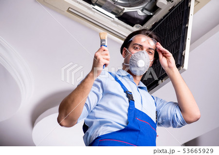 Young repairman repairing ceiling air conditioning unit  53665929