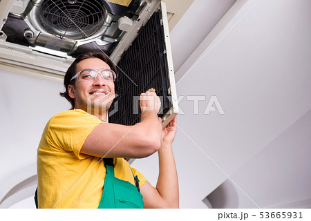 Young repairman repairing ceiling air conditioning unit  53665931