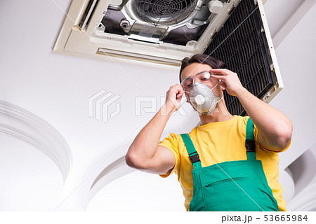 Young repairman repairing ceiling air conditioning unit  53665984