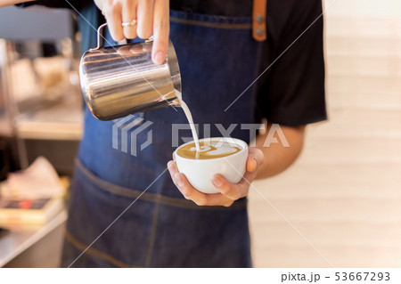 Barista hand pour milk making latte art coffee at cafe. Barista hand pour milk making latte art coffee at cafe. 53667293