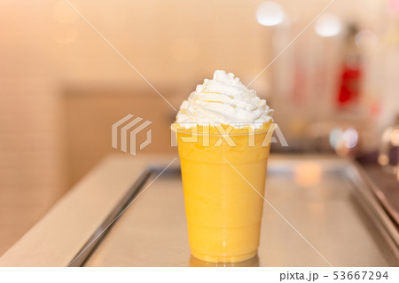 Fresh orange smoothie in plastic glass with cream on top. Fresh orange smoothie in plastic glass with cream on top. 53667294