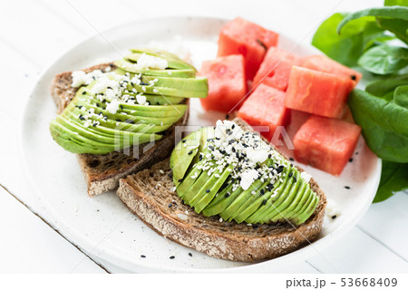 Sliced avocado with soft white cheese on toast 53668409