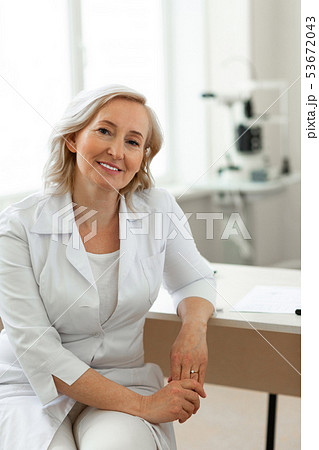 Short-haired doctor with light smile wearing white uniform Short-haired doctor with light smile wearing white uniform 53672043
