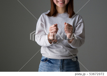 手錠を掛けられた女の子が微笑んでいる警察違反犯人の写真素材