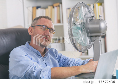 Man suffers from heat in the office or at home 53672436